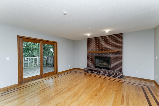 2319 Viola View Ln NE, Rochester, MN 55906 - unfurnished living room featuring wood finished floors, a brick fireplace, and a textured ceiling