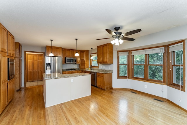 2319 Viola View Ln NE, Rochester, MN 55906 - kitchen featuring appliances with stainless steel finishes, light wood-style floors, a kitchen island, and brown cabinets