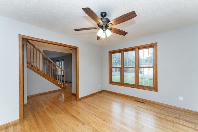 2319 Viola View Ln NE, Rochester, MN 55906 - empty room with light wood-style flooring, stairs, ceiling fan, and a textured ceiling