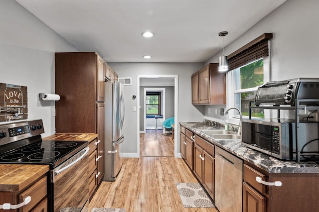 3256 Sheridan Ave N, Minneapolis, MN 55412 - kitchen with stainless steel appliances, light wood-type flooring, pendant lighting, recessed lighting, and brown cabinets