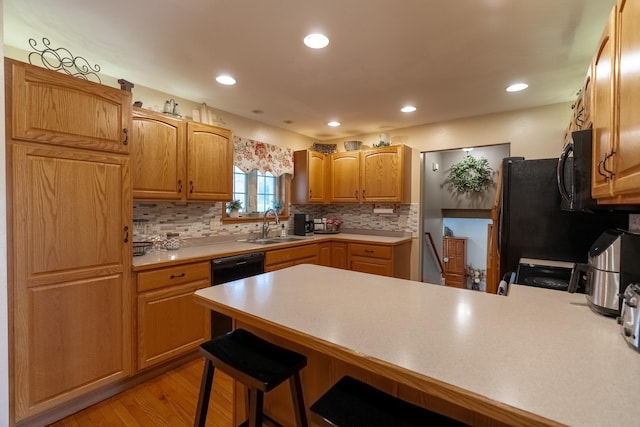 704 Main St, Madelia, MN 56062 - kitchen with a peninsula, tasteful backsplash, light countertops, light wood-type flooring, and a breakfast bar area