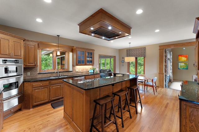 11582 Raspberry Hill Rd, Eden Prairie, MN 55344 - kitchen featuring a warming drawer, appliances with stainless steel finishes, light wood-style flooring, a kitchen island, and dark stone countertops