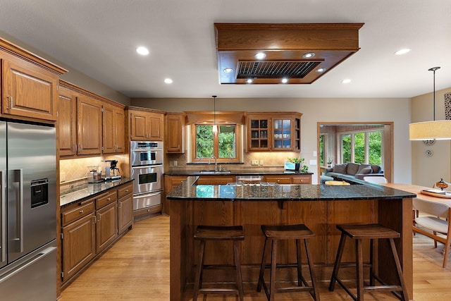 11582 Raspberry Hill Rd, Eden Prairie, MN 55344 - kitchen featuring stainless steel appliances, a warming drawer, light wood-style floors, a breakfast bar, and backsplash