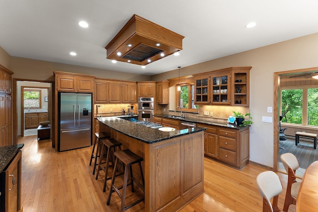 11582 Raspberry Hill Rd, Eden Prairie, MN 55344 - kitchen with appliances with stainless steel finishes, a kitchen bar, brown cabinetry, backsplash, and recessed lighting