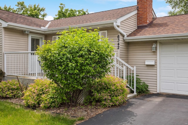 6342 Baker Ave NE, Fridley, MN 55432 - view of home's exterior featuring a shingled roof, a chimney, a garage, stairway, and asphalt driveway