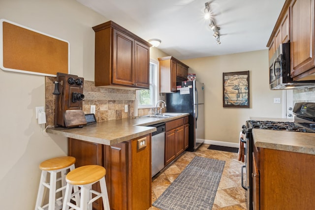 6342 Baker Ave NE, Fridley, MN 55432 - kitchen with stainless steel appliances, tasteful backsplash, a kitchen breakfast bar, and brown cabinets
