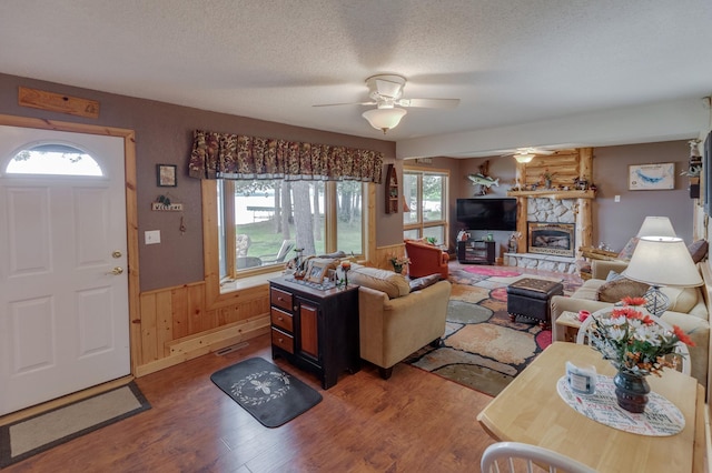 35139 County 39, Laporte, MN 56461 - living room with wood finished floors, a wainscoted wall, a ceiling fan, a textured ceiling, and a fireplace