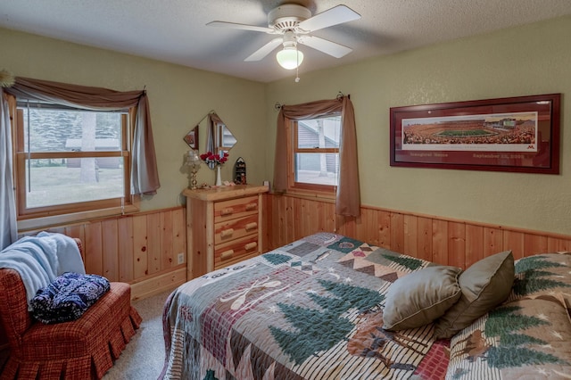 35139 County 39, Laporte, MN 56461 - carpeted bedroom with wood walls, a wainscoted wall, a textured ceiling, and ceiling fan