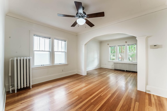 1787 Randolph Ave, Saint Paul, MN 55105 - unfurnished room featuring radiator heating unit, arched walkways, light wood-type flooring, ceiling fan, and crown molding