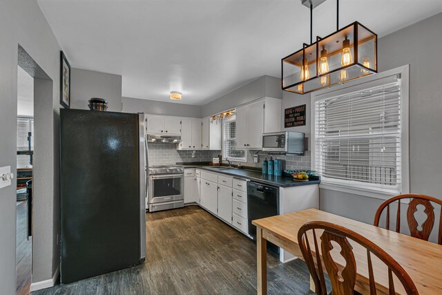 212 30th Ave N, Saint Cloud, MN 56303 - kitchen with appliances with stainless steel finishes, dark countertops, dark wood finished floors, white cabinetry, and backsplash