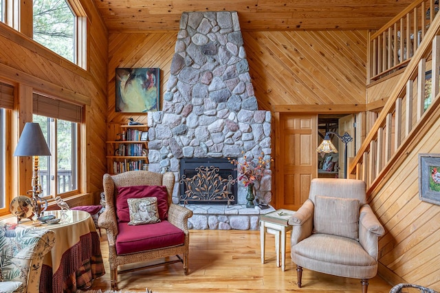 1116 Sand Lake Dr NW, Backus, MN 56435 - sitting room featuring wooden walls, a stone fireplace, stairs, hardwood / wood-style flooring, and a towering ceiling