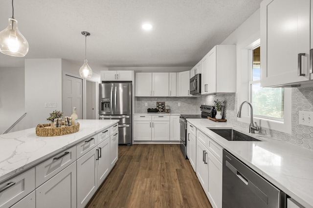 4909 98th St, Bloomington, MN 55437 - kitchen with appliances with stainless steel finishes, dark wood-type flooring, tasteful backsplash, white cabinetry, and pendant lighting