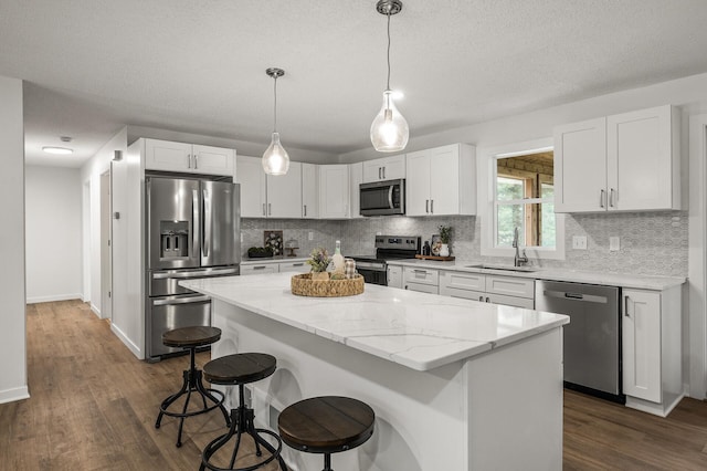 4909 98th St, Bloomington, MN 55437 - kitchen with appliances with stainless steel finishes, a kitchen island, a breakfast bar area, tasteful backsplash, and a textured ceiling