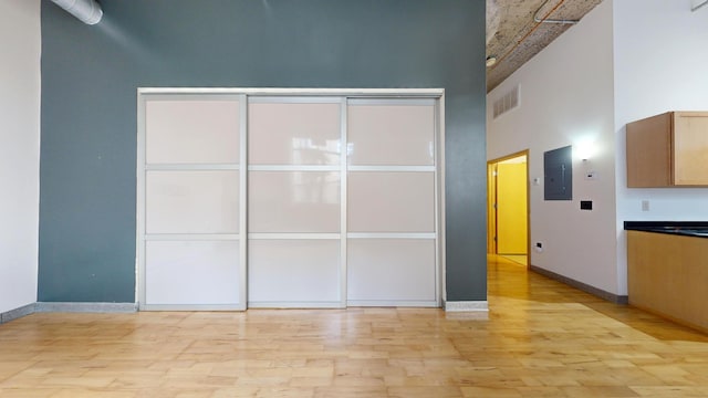 521 7th St Unit 519, Minneapolis, MN 55415 - unfurnished bedroom with electric panel, light wood finished floors, a towering ceiling, and a closet