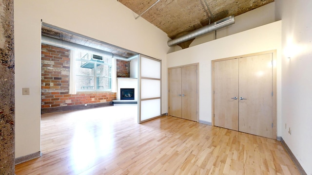 521 7th St Unit 519, Minneapolis, MN 55415 - unfurnished living room with wood finished floors, a fireplace with raised hearth, and a towering ceiling