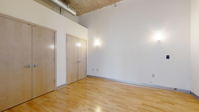 521 7th St Unit 519, Minneapolis, MN 55415 - unfurnished bedroom with multiple closets, light wood-style floors, and a towering ceiling
