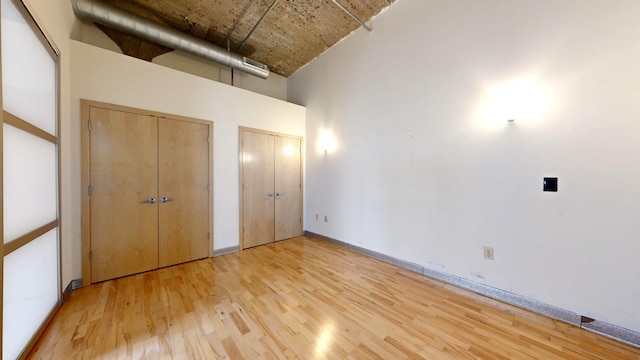 521 7th St Unit 519, Minneapolis, MN 55415 - unfurnished bedroom featuring two closets, light wood-style flooring, and a high ceiling