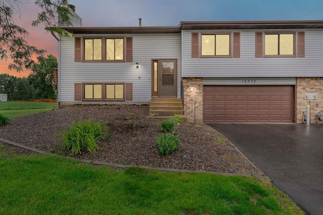 12277 Fillmore St NE, Blaine, MN 55434 - bi-level home featuring an attached garage, entry steps, driveway, a chimney, and brick siding