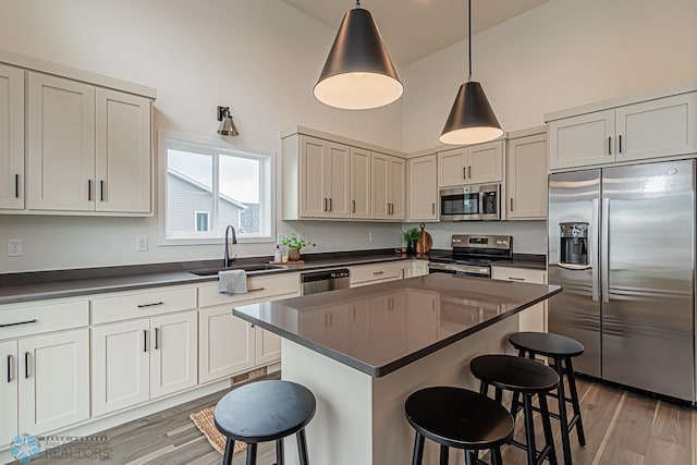 6724 32nd St S, Fargo, ND 58104 - kitchen featuring appliances with stainless steel finishes, high vaulted ceiling, dark countertops, and a kitchen breakfast bar