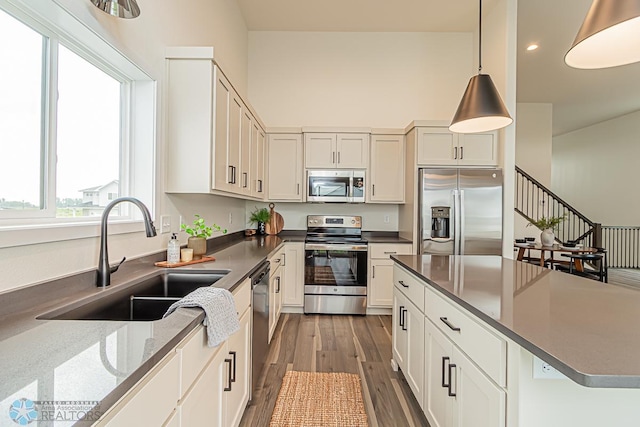 6724 32nd St S, Fargo, ND 58104 - kitchen with stainless steel appliances, wood finished floors, pendant lighting, recessed lighting, and white cabinetry
