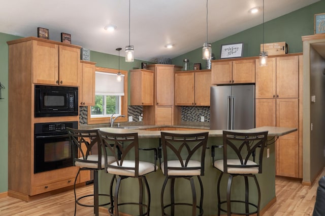 N8343 Mcwain Dr, Holland Twp, WI 54636 - kitchen with black appliances, vaulted ceiling, tasteful backsplash, light wood-type flooring, and a center island