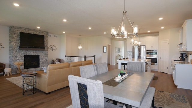 1872 Oakpointe Dr, Waconia, MN 55387 - dining space featuring a chandelier, dark wood finished floors, recessed lighting, and a fireplace
