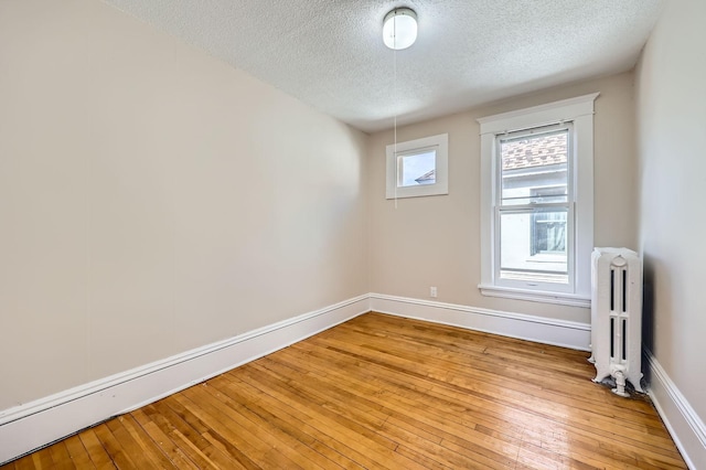 3148 Pleasant Ave, Minneapolis, MN 55408 - spare room with radiator heating unit, a textured ceiling, and light wood-style floors