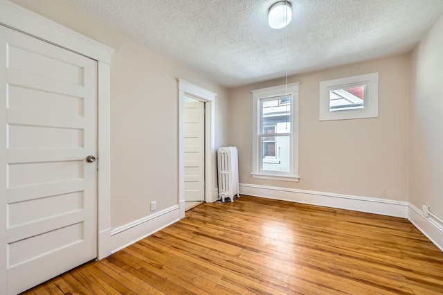 3148 Pleasant Ave, Minneapolis, MN 55408 - empty room with radiator, a textured ceiling, and light wood-style floors