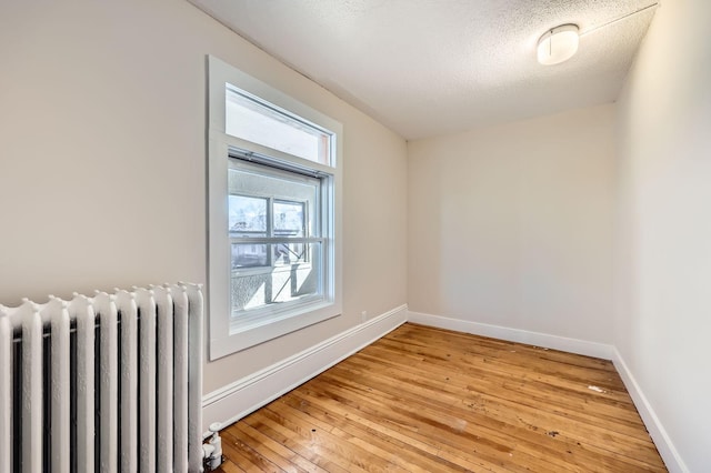 3148 Pleasant Ave, Minneapolis, MN 55408 - empty room featuring radiator heating unit, light wood-style floors, and a textured ceiling
