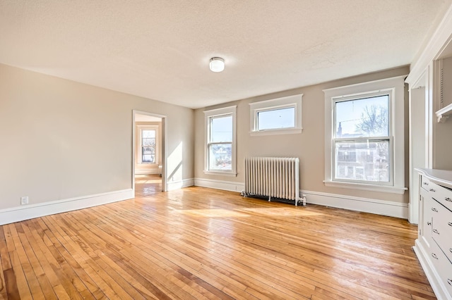 3148 Pleasant Ave, Minneapolis, MN 55408 - unfurnished living room with radiator heating unit, light wood-style flooring, plenty of natural light, and a textured ceiling