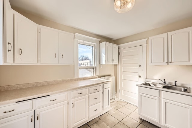 3148 Pleasant Ave, Minneapolis, MN 55408 - kitchen featuring radiator, white cabinetry, light tile patterned floors, and light countertops