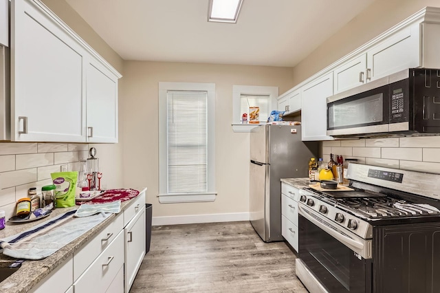 3148 Pleasant Ave, Minneapolis, MN 55408 - kitchen with stainless steel appliances, white cabinetry, light countertops, light wood-style floors, and tasteful backsplash
