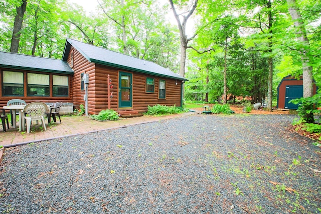 1962 81st St, Balsam Lake, WI 54810 - view of front of home with a storage shed, faux log siding, a patio, and entry steps