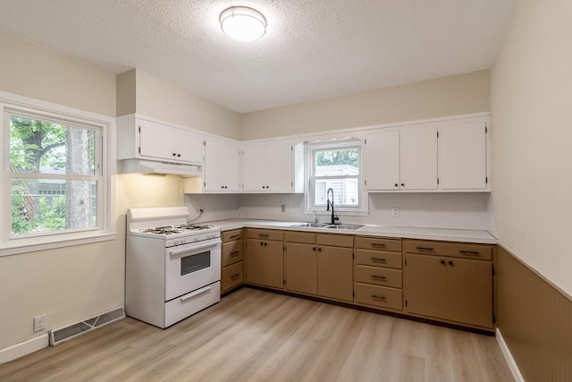 500 Sherman St, North Mankato, MN 56003 - kitchen featuring white range with gas stovetop, under cabinet range hood, light wood finished floors, a textured ceiling, and light countertops