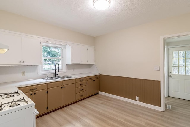 500 Sherman St, North Mankato, MN 56003 - kitchen featuring a wainscoted wall, light wood finished floors, gas range gas stove, light countertops, and a textured ceiling