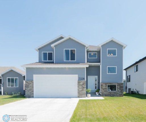 7328 Aquiline Dr S, Fargo, ND 58104 - view of front of home with concrete driveway, a front lawn, and an attached garage