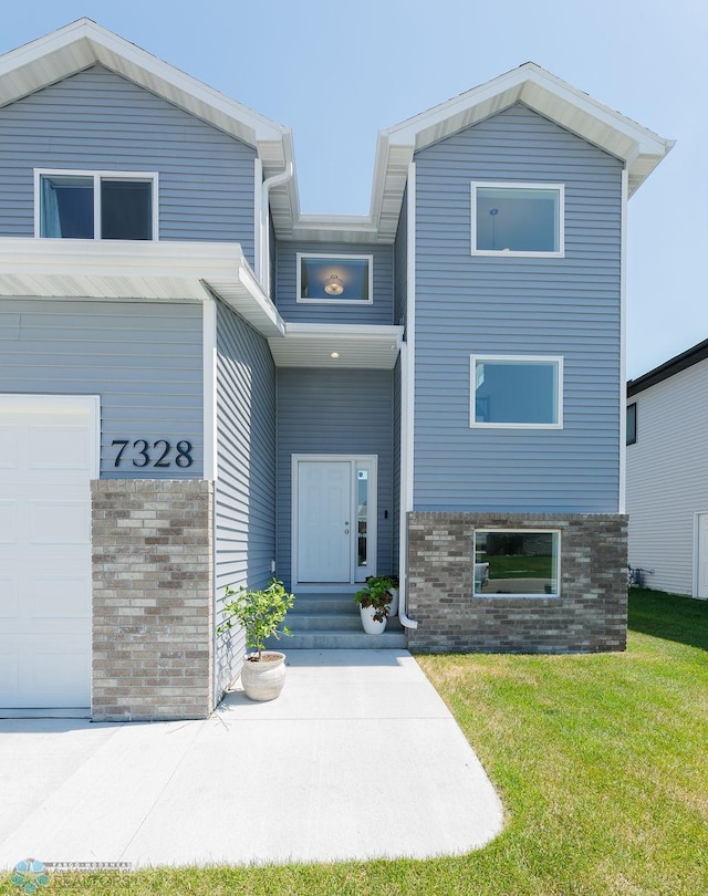 7328 Aquiline Dr S, Fargo, ND 58104 - view of front of property featuring brick siding, a garage, and a front yard