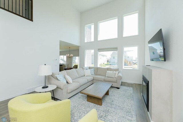 7328 Aquiline Dr S, Fargo, ND 58104 - living area featuring wood finished floors, a chandelier, a high ceiling, and a glass covered fireplace