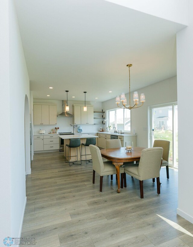 7328 Aquiline Dr S, Fargo, ND 58104 - dining room featuring light wood-type flooring, a chandelier, recessed lighting, and arched walkways