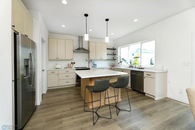 7328 Aquiline Dr S, Fargo, ND 58104 - kitchen with stainless steel appliances, wall chimney range hood, recessed lighting, wood finished floors, and a breakfast bar