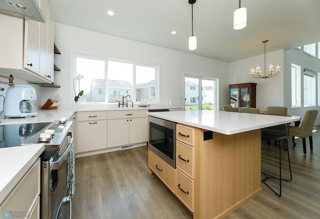 7328 Aquiline Dr S, Fargo, ND 58104 - kitchen featuring appliances with stainless steel finishes, a kitchen island, wood finished floors, a chandelier, and recessed lighting