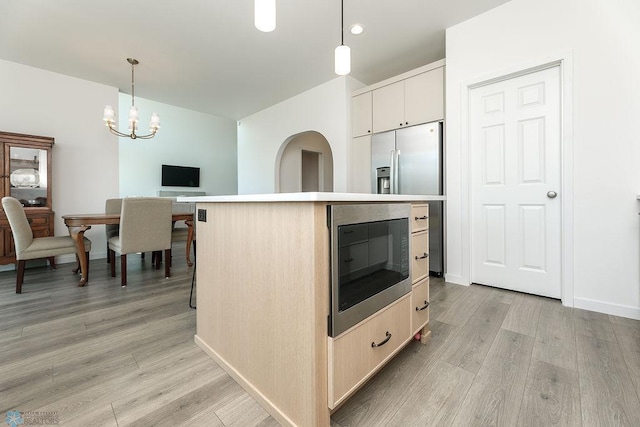 7328 Aquiline Dr S, Fargo, ND 58104 - kitchen featuring appliances with stainless steel finishes, light wood-style flooring, a kitchen island, a chandelier, and decorative light fixtures