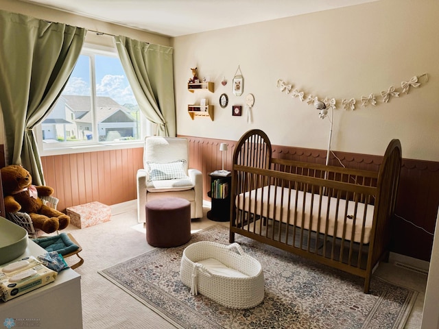 7328 Aquiline Dr S, Fargo, ND 58104 - carpeted bedroom with wainscoting, wooden walls, and a crib