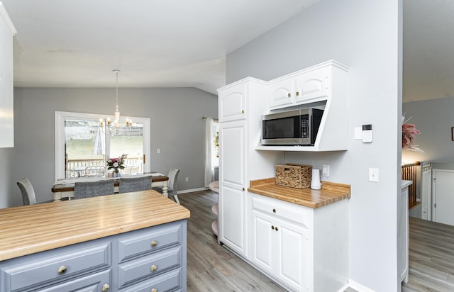 5520 25th Ave NW, Rochester, MN 55901 - kitchen with stainless steel microwave, light wood-type flooring, a chandelier, lofted ceiling, and white cabinets