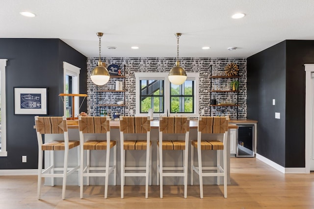 7568 Glen Alcove, Woodbury, MN 55129 - community bar area featuring beverage cooler, light wood finished floors, an accent wall, recessed lighting, and hanging light fixtures