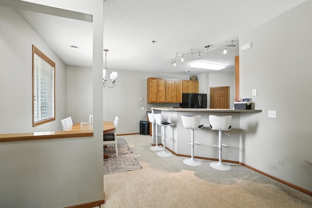 451 Frederick Cir Unit 1405, Hastings, MN 55033 - kitchen with black fridge, a kitchen breakfast bar, light colored carpet, a chandelier, and a textured ceiling