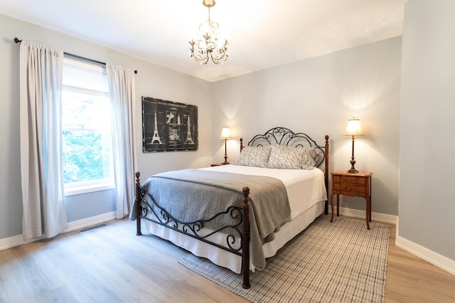 6045 Galpin Lake Rd, Shorewood, MN 55331 - bedroom with a chandelier, wood finished floors, and multiple windows