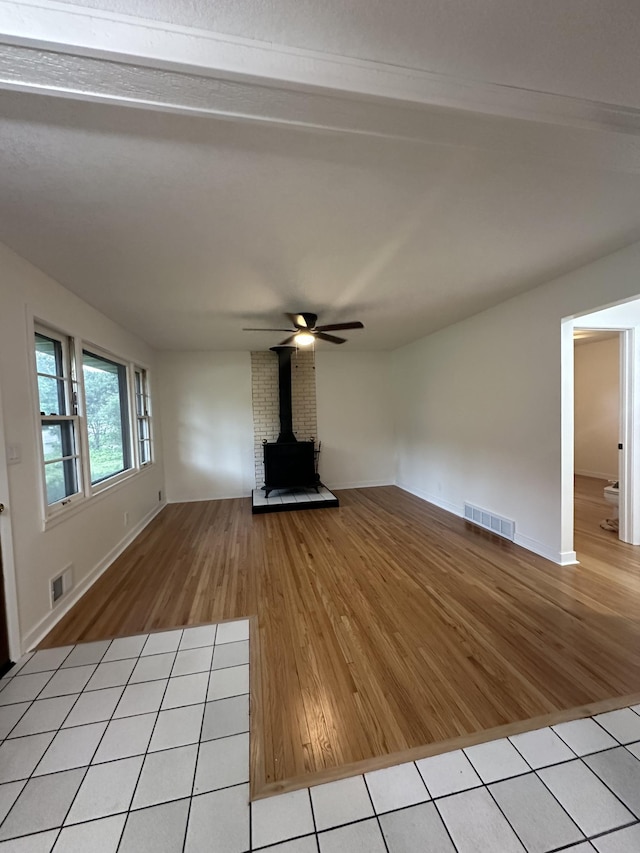 2325 Crosstown Blvd NE, Ham Lake, MN 55304 - unfurnished living room with a wood stove, light wood-style floors, and a ceiling fan
