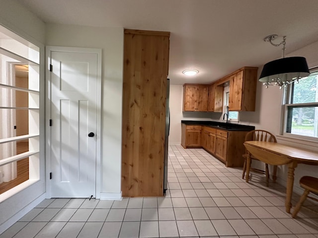 2325 Crosstown Blvd NE, Ham Lake, MN 55304 - kitchen with light tile patterned floors, dark countertops, brown cabinetry, and hanging light fixtures