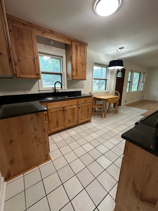 2325 Crosstown Blvd NE, Ham Lake, MN 55304 - kitchen with dark countertops, a textured ceiling, light tile patterned floors, brown cabinetry, and hanging light fixtures